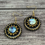 Handmade drop earrings with abalone shell button, seed beads, 24kt gold beads, hide backing, and 18kt gold hooks, 2” long.