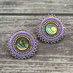 Handmade drop earrings with abalone shell button, seed beads, 24kt gold beads, hide backing, and 925 silver studs, 1 inch long.