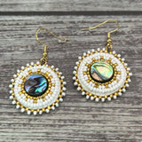 Handmade drop earrings with abalone shell button, seed beads, 24kt gold beads, hide backing, and 18kt gold hooks, 2” long.