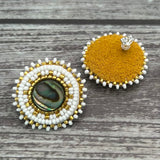 Handmade drop earrings with abalone shell button, seed beads, 24kt gold beads, hide backing, and 925 silver studs, 1 inch long.