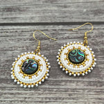 Handmade drop earrings with abalone shell button, seed beads, 24kt gold beads, hide backing, and 18kt gold hooks, 2” long.