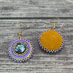 Handmade drop earrings with abalone shell button, seed beads, 24kt gold beads, hide backing, and 18kt gold hooks, 2” long.