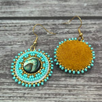 Handmade drop earrings with abalone shell button, seed beads, 24kt gold beads, hide backing, and 18kt gold hooks, 2” long.