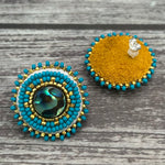 Handmade drop earrings with abalone shell button, seed beads, 24kt gold beads, hide backing, and 925 silver studs, 1 inch long.