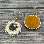 Handmade drop earrings with abalone shell button, seed beads, 24kt gold beads, hide backing, and 18kt gold hooks, 2” long.
