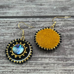 Handmade drop earrings with abalone shell button, seed beads, 24kt gold beads, hide backing, and 18kt gold hooks, 2” long.