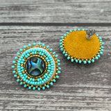 Handmade drop earrings with abalone shell button, seed beads, 24kt gold beads, hide backing, and 925 silver studs, 1 inch long.