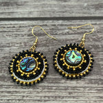 Handmade drop earrings with abalone shell button, seed beads, 24kt gold beads, hide backing, and 18kt gold hooks, 2” long.