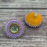 Handmade drop earrings with abalone shell button, seed beads, 24kt gold beads, hide backing, and 925 silver studs, 1 inch long.