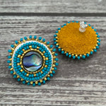 Handmade drop earrings with abalone shell button, seed beads, 24kt gold beads, hide backing, and 925 silver studs, 1 inch long.