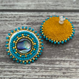 Handmade drop earrings with abalone shell button, seed beads, 24kt gold beads, hide backing, and 925 silver studs, 1 inch long.